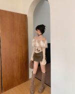 Woman wearing a fluffy y2k aesthetic top with sleeves, standing in an arched doorway.