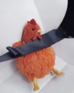 Close-up of a plush fat chicken, product_keyword, resting on a car seat.