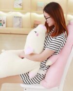 A white kawaii piggy plushie resting on a chair, held by a person.