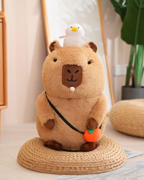 Capybara plushie with a duck and carrot accessory. Soft, cuddly toy.