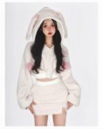 Woman wearing bunny hooded plush pajamas, soft pink and white fleece set.