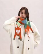 Cute fox scarf featuring a fox head design with orange, blue, and green accents. Cozy knit fox scarf.