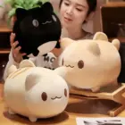 Two Round Neko Plushies, a black and a white, displayed on a wooden table.