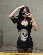 Woman wearing a skull printed gothic aesthetic dress, black top, and lace lingerie. Close-up fashion shot.