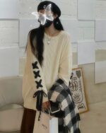 Cream-colored Korean aesthetic sweater with bow accents and a unique design.