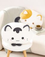 Two kawaii cat plushies, one white and one yellow, displayed on a table.