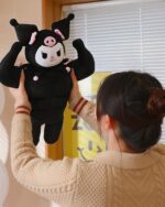 A black Kuromi sanrio muscular plushie, a Strong Squishy Crew member, being held.