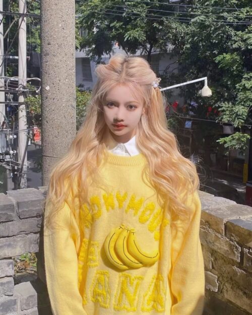 A person wearing a yellow vintage banana sweater with banana illustrations.