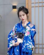 Woman wearing a blue short floral kimono with pink and white blossoms, Japanese aesthetic.