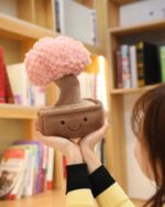 Close-up of a brown plush potted tree with a pink fluffy top, the plush potted tree is being held.