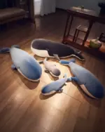 Three kawaii whale plushies - Bubbles, Luna, and one gray whale, on a wooden floor.