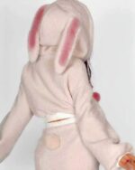 Close-up of bunny hooded plush pajamas, soft beige fabric with pink ears and tail.