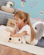 Large grey big bunny plushie resting on a rug, next to a woman.