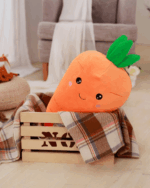 Cute orange kawaii carrot plushie with a green leafy top, resting on a plaid blanket.