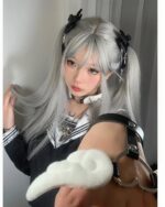 Close-up of a person's hand wearing Winged Love Bracelets, featuring a fluffy white pompom and metal cuffs, in a Harajuku style.