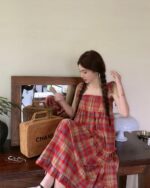 Red and black plaid french vintage suspender skirt worn by a woman indoors.