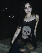Woman wearing a skull printed tight dress with gothic aesthetic, featuring lace trim and a cross necklace.