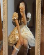 A cream-colored vintage aesthetic dress with a square collar and ruffled details.