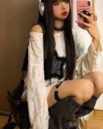 Woman wearing a grunge star top with layered, distressed fabric and black headphones.