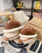 Two brown mushroom homunculus plushies on a black road rug.