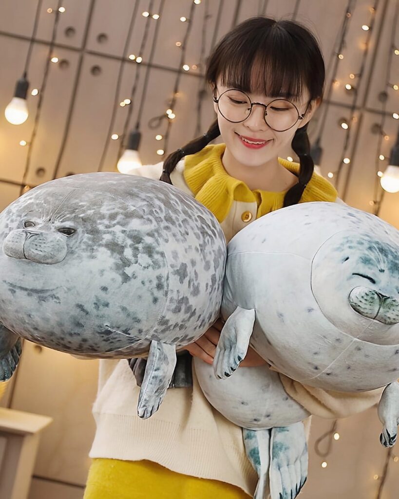 Two yuki the seal plush toys being held by a woman.