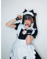Person wearing a cat maid cosplay outfit, featuring a black and white apron and cat ears.
