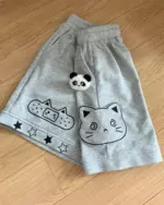 Gray kawaii neko shorts with cat, bandage, and panda motifs on a wooden floor.