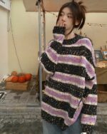 A black and purple y2k striped sweater worn by a person outdoors.