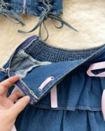 Close-up of a blue denim coquette denim set featuring a ruffled skirt and tie details.