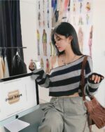 Model wearing a retro aesthetic sweater with an off-the-shoulder design.