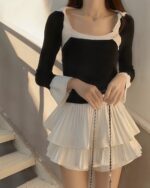 White pleated coquette aesthetic skirt layered over a black long-sleeve top.