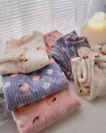 Pile of korean aesthetic pajamas featuring bear print and coral colors. Soft, plush fabric.