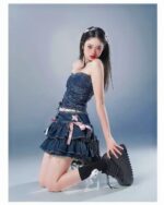 Model wearing a laced denim mini skirt - Y2k aesthetic skirt with corset and pink accents.