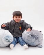 Child holding Yuki the Seal Plush and another yuki the seal plush toy.