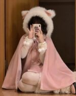 Person wearing a pink lolita hooded coat and matching earmuffs, holding a phone.