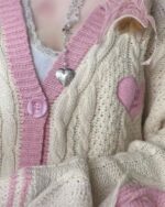 Close-up of a cream-colored kawaii embroidered sweater featuring pink accents and heart details.