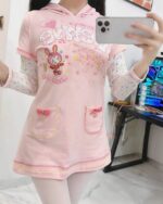 Close-up of a pink pastel hooded dress with a cute, cartoon-themed design and pockets.