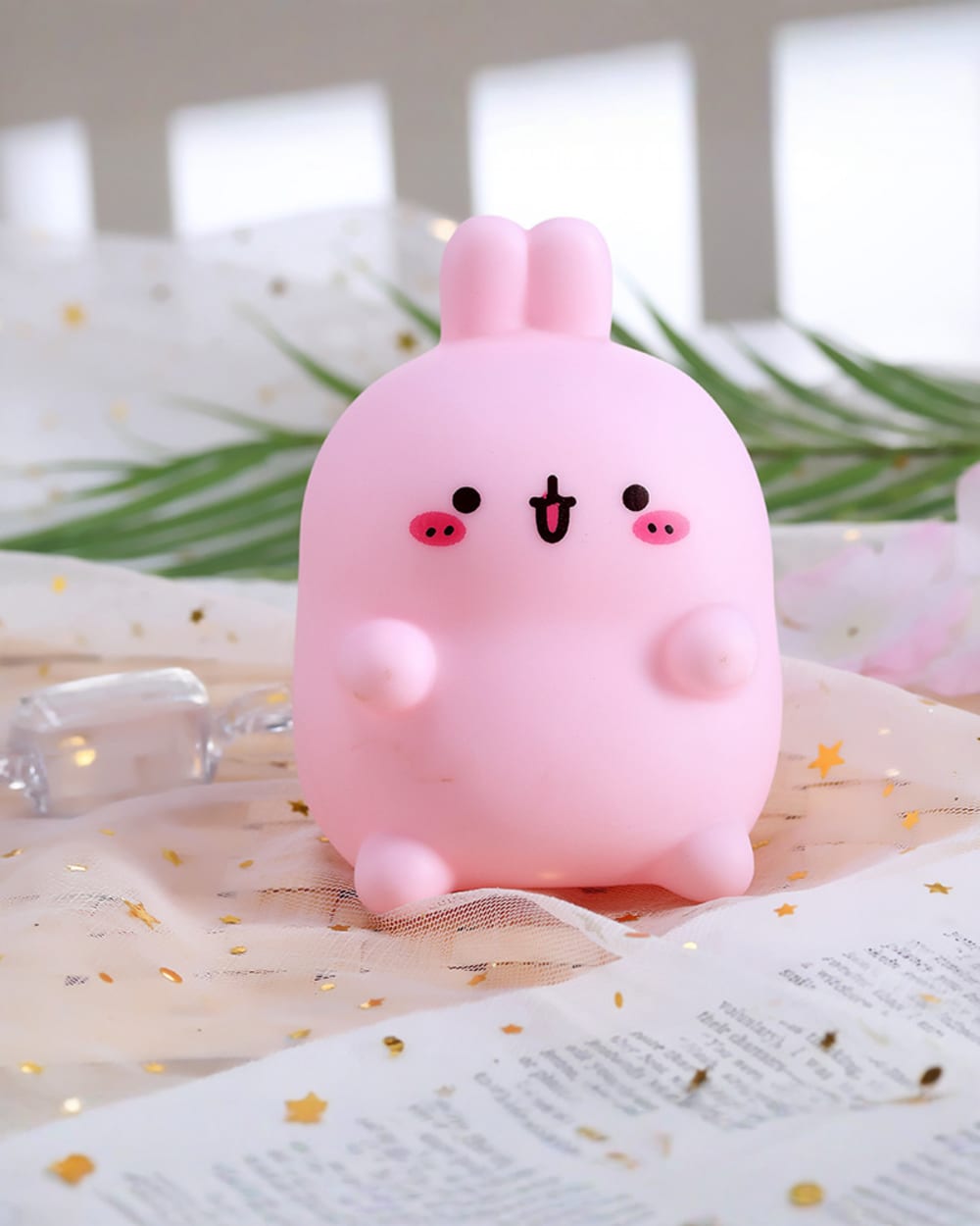 Pink molang bunny lamp on a patterned surface, soft lighting.