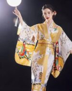 Satin Japanese kimono featuring a yellow and white design with floral and landscape motifs.