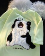 Japanese-style sleepy cat t-shirt featuring an embroidered, plush cat design on a light green shirt.