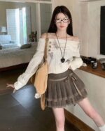 Model wearing a pleated Korean aesthetic skirt with lace trim and a matching sweater.