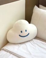 Kawaii happy cloud plushie resting on a white bedsheet.