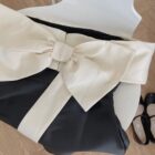 Close-up of a french aesthetic dress featuring a large satin bow detail and black fabric.