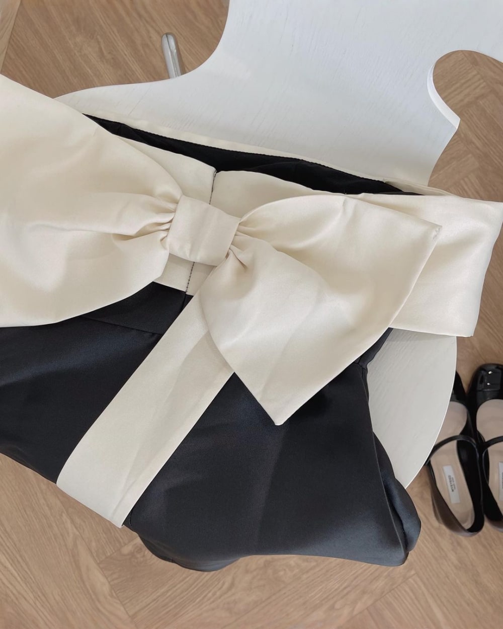 Close-up of a french aesthetic dress featuring a large satin bow detail and black fabric.