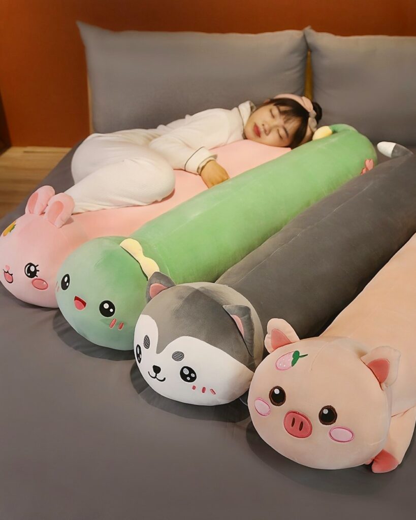 Multiple kawaii sleeping pillows in various animal designs on a bed.