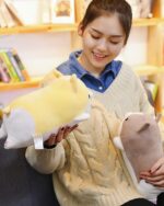 Close-up of a yellow kawaii corgi plushie held by a woman.