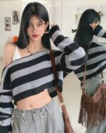Off-the-shoulder retro aesthetic sweater in gray and black stripes, showcasing a cropped knit design.