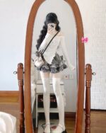 Woman wearing a y2k lolita set: long-sleeved top and layered skirt with thigh-high socks and shoes.