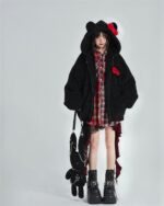 Model wearing a black, hooded jacket and a checkered punk lolita skirt with a plaid shirt and boots.