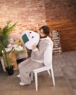 Close-up of a brown kawaii onigiri plushie, soft and huggable, held by a person in a robe.